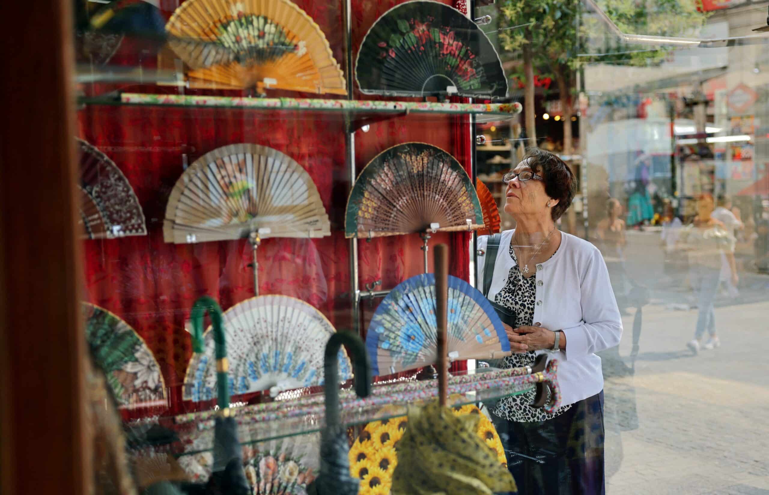 A woman looks at the window of Casa de Diego hand fan store in Madrid, on July 8, 2025. The Spanish must-have fan has retained its relevance amid increasingly oppressive summer temperatures stoked by climate change. (Photo by Thomas COEX / AFP)