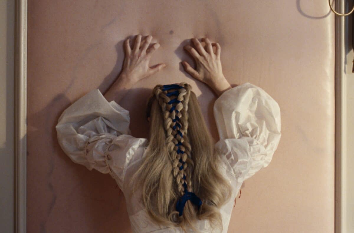 Las trenzas de Cathry emulan un corsé con cintas. Foto de Warner Bros.