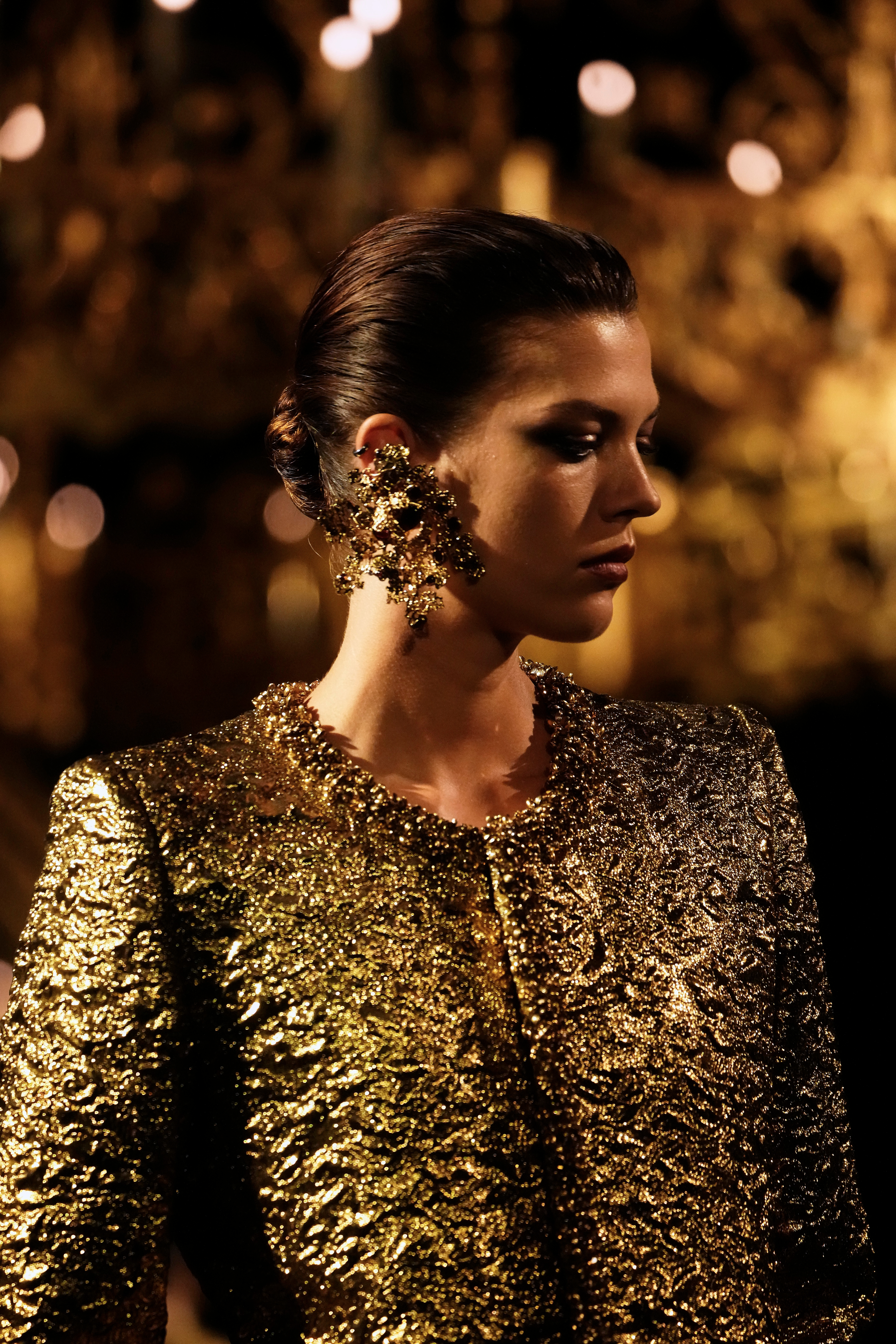 A model presents a design heavy with gold embroidery